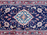 A hand-knotted Persian Sarough hall runner rug with a traditional floral design in indigo blue, beige, red, and peach tones.