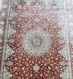 A hand-knotted pure silk Persian Qum rug with a salmon pink and terracotta tone, featuring a dome medallion floral design.