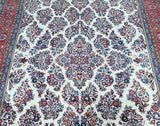 A detailed image of a hand-knotted Persian Sarough rug featuring a floral pattern in various colors on a white background.