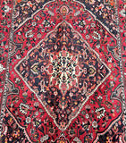 A vintage Persian Bakhtiari rug with a bold central medallion floral design, featuring a mix of colors including red, terracotta, beige, blue, orange, yellow, brown, and charcoal.