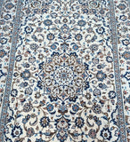 Close-up of a patterned Persian Kashan rug with intricate designs in blue, brown, and beige.