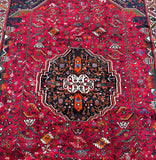 A vibrant, multicolored Persian Qashqai Shiraz rug with a geometric and floral design, featuring a central medallion.