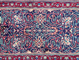 Close-up of a floral patterned Persian Sarough hall runner rug with intricate designs in red, blue, and white.
