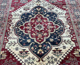 Close-up of a patterned rug with intricate designs in red, blue, and white.