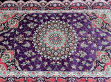 Decorative pure silk Persian Qum rug with intricate patterns and a central mandala design on a purple background.