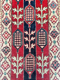 Close-up of a patterned Afghan Kazak runner with red, blue, and beige colors.