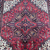 A hand knotted Persian Heriz rug with a geometric broken branch design, featuring a dense pile and a mix of rustic red, beige, brown, black, and blue colors.