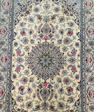 A hand-knotted wool and silk Persian Isfahan rug with a floral design, featuring beige and gold tones, and a silk foundation.