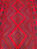 A detailed shot of a Tribal Afghan Meymaneh Kilim Rug featuring a geometric diamond medallion tribal pattern in red, black, and blue colors on a wool base.