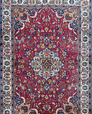 An antique Persian Ghiasabad rug with a central medallion floral design, surrounded by a border with detailed geometric patterns. The rug has a rich red, beige, blue, orange, yellow, and pink tone.
