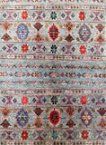 Patterned Afghan Kazak rug with geometric and floral designs in red, blue, and multicolor on a blue background.