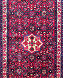 A traditional Persian-style area rug with a vibrant red field, featuring a central cream-colored medallion surrounded by pink and blue floral motifs, and intricate geometric borders.