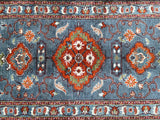 A hand-knotted Afghan hall runner rug with a floral design in various colors on a duck egg blue background.