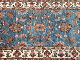 Close-up view of a hand-knotted Afghan Chobi hall runner featuring a floral design with light blue, caramel, orange, beige, green, and brown tones on a cotton base.