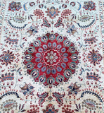 Close-up of a handmade Afghan Chobi Rug featuring a central floral design with intricate patterns in beige, gold, maroon, green, and blue tones.