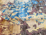 A Contemporary Afghan Chobi Rug with a geometric pattern featuring beige, brown, gold and blue tones, handmade and laid out on the floor.