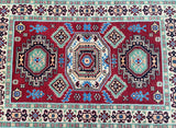 A rectangular, flatweave tribal Afghan Kazak rug with a geometric medallion design, featuring a combination of red, beige, blue, green, and yellow tones.