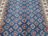 A detailed view of a blue and red hand-knotted Afghan Kazak rug with a geometric and floral pattern.