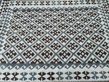 A rectangular, flatweave Afghan kilim rug with geometric tribal patterns in beige, gray, and brown tones.