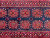 A hand-knotted Afghan hall runner, pile rug with a geometric and floral design in red, blue, and burgundy tones on a dark background.
