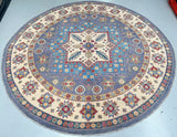 Round decorative Afghan rug with intricate patterns on a light blue floor.