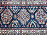 Close-up of a hand-knotted Afghan Super Kazak hall runner featuring geometric design with navy blue, beige, red, gold, and orange colors.