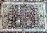 A detailed view of a chocolate brown, beige, navy blue, turquoise, and orange tone dyed super kazak rug with a semi geometric, semi floral design, hand-spun ghazni wool pile on a cotton base.