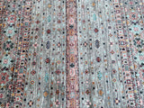 A traditional hand-knotted Afghan Khorjin Kazak rug with a geometric pattern, featuring beige, grey, brown, blue, green and red tones, on a cotton base.