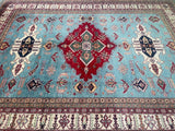 A detailed shot of a multicolored, geometric patterned Afghan Super Kazak rug with a central red and blue medallion design, and fringed edges.