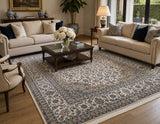 A large traditional oriental area rug with an intricate navy blue and beige floral pattern, styled in a bright, modern living room with cream sofas, a wooden coffee table, and hardwood floors.