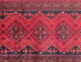 Close-up of a red and black Afghan hall runner rug ntricate designs.