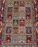 A rectangular, hand-knotted woolen rug with a floral garden design in a multitude of colors on a cotton base.