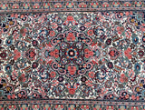 An ornate Persian Bijar area rug with a dense floral and vine pattern, featuring a cream background with red, blue, green, and purple motifs.