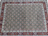 A detailed image of a Persian Birjand rug featuring a geometric pattern with a central fish design, in a variety of colors including beige, orange, red, green, blue, and pink.