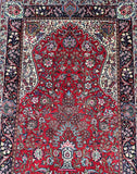 A traditional handmade Persian Ghiasabad rug with a floral Gate of Paradise design and a tree of life motif, predominantly in red and beige colors.