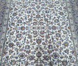 A close-up view of a traditional Persian Kashan rug with a floral Afshan design, featuring colors such as beige, indigo blue, and purple.