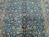 A detailed view of a Persian Kashmar rug with a floral pattern in blue, beige, yellow, orange, and indigo blue tones.