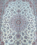 A finely woven Persian Nain rug with a central medallion floral design and rosette motifs, in beige, blue, pink, green, and burgundy tones.
