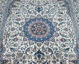 A traditional Persian Nain rug with a central medallion floral design, featuring beige, blue, black, brown, and burgundy tones on a cotton base with lamb's wool and silk inlaid pile.