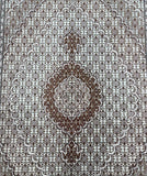 A traditional Persian Tabriz area rug with an intricate geometric and floral pattern in brown, beige, and white, featuring a large central medallion.