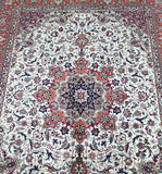 A detailed image of a hand-knotted Persian Tabriz rug featuring a central medallion floral design with a color palette including beige, orange, blue, burgundy, black, and green.