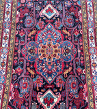A detailed image of a Tribal Persian Tuserkan Rug featuring a geometric pattern with a central medallion design and animal motifs in a bordered area.