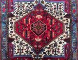 A hand-knotted, square-shaped, tribal Persian Nahavand rug with a geometric and semi-floral design, featuring a central hexagonal pattern surrounded by a border in beige, blue, red, pink, orange, and brown tones.
