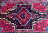 A vibrant, intricately designed Tribal Persian Tuserkan rug with a central medallion and geometric patterns in a variety of colors including red, blue, beige, green, and orange.