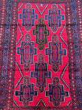 A vibrant red and multicolored geometric patterned Afghan Balouchi rug with a border in a contrasting color.