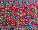 A close-up of a traditional Persian Kashan hall runner rug with a floral pattern in red, blue, beige, pink, yellow, and green tones.