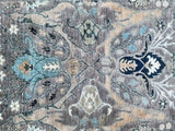 Decorative rug with floral patterns in blue, beige, and gray on a dark background