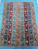 A long, hand-knotted Afghan Super Kazak rug with a geometric stripe pattern in multiple colors, including blue, red, and beige, showcasing intricate floral and geometric detailing.