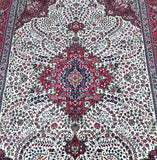 A detailed image of a Persian Tabriz rug with a central medallion floral design, featuring a pure wool pile on a sturdy cotton base, in shades of beige, blue, red, black, and pink and green.