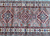 A hand woven Afghan hall runner featuring a geometric caucasian design in multiple colors including beige, light brown, grey, green, maroon, blue, terracotta, and orange.
